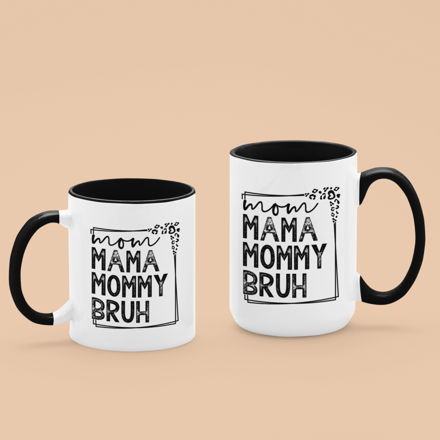 11 & 15 oz white ceramic mug with a black interior and handle. The mug features the black text "mom MAMA MOMMY BRUH" stacked vertically within a rectangular frame with leopard print accents. Dried citrus slices and small white flowers are arranged near the base of the mug.