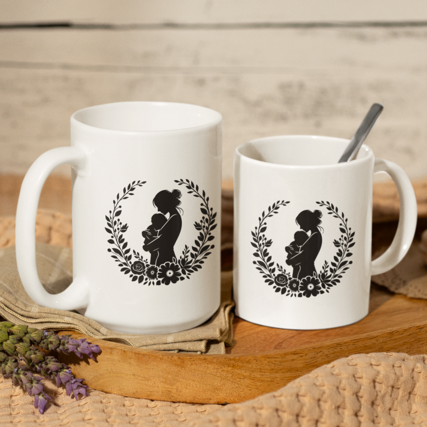 Charming white ceramic mug featuring a tender black silhouette of a mother cradling her baby, framed by a delicate floral wreath. This mug radiates love and comfort. Ideal for gifting to new moms, celebrating Mother’s Day, or honoring the beauty of motherhood. Durable, dishwasher and microwave safe—perfect for everyday coffee, tea, or cocoa moments.