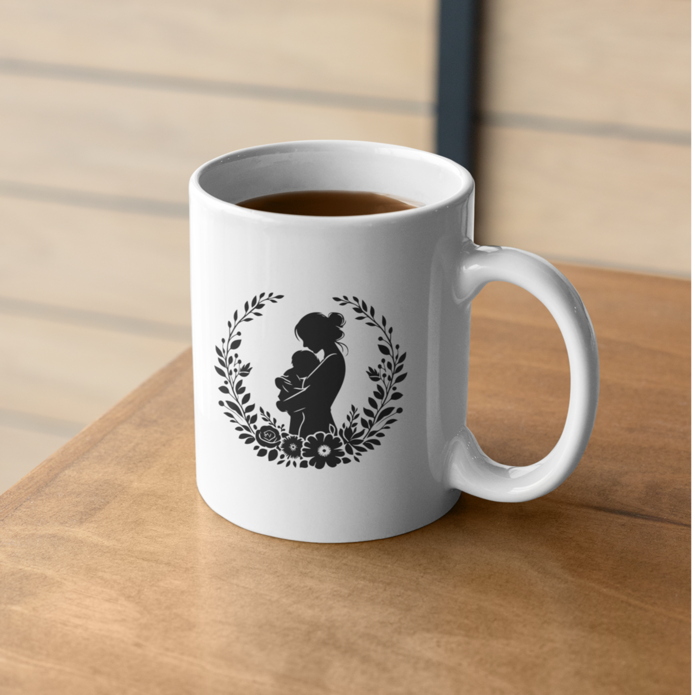 Charming white ceramic mug featuring a tender black silhouette of a mother cradling her baby, framed by a delicate floral wreath. This mug radiates love and comfort. Ideal for gifting to new moms, celebrating Mother’s Day, or honoring the beauty of motherhood. Durable, dishwasher and microwave safe—perfect for everyday coffee, tea, or cocoa moments.