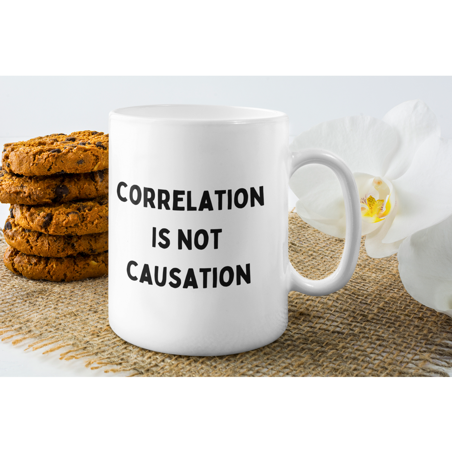 11 oz white ceramic coffee mug displayed on a light surface, filled with coffee. Bold black text on the front reads "CORRELATION IS NOT CAUSATION," with an intentional typo where "CAUSATION" is spelled "CAUSATION." The sturdy handle and high-quality finish offer both comfort and durability.