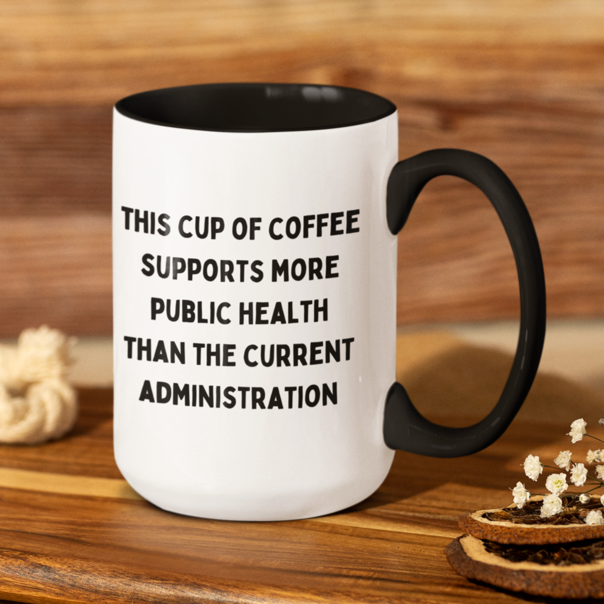 15 oz white ceramic coffee mug with a sleek black handle and black interior. The mug features a bold, humorous message in black, all-caps text that reads: "THIS CUP OF COFFEE SUPPORTS MORE PUBLIC HEALTH THAN THE CURRENT ADMINISTRATION." Perfect for health professionals, activists, or anyone with a sharp sense of humor and passion for public health.