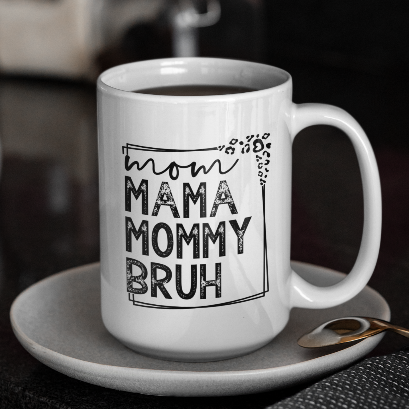 15 oz white mug displaying a playful design that reads "mom MAMA MOMMY BRUH" in black, framed with leopard print details. A funny gift for moms with a sense of humor.