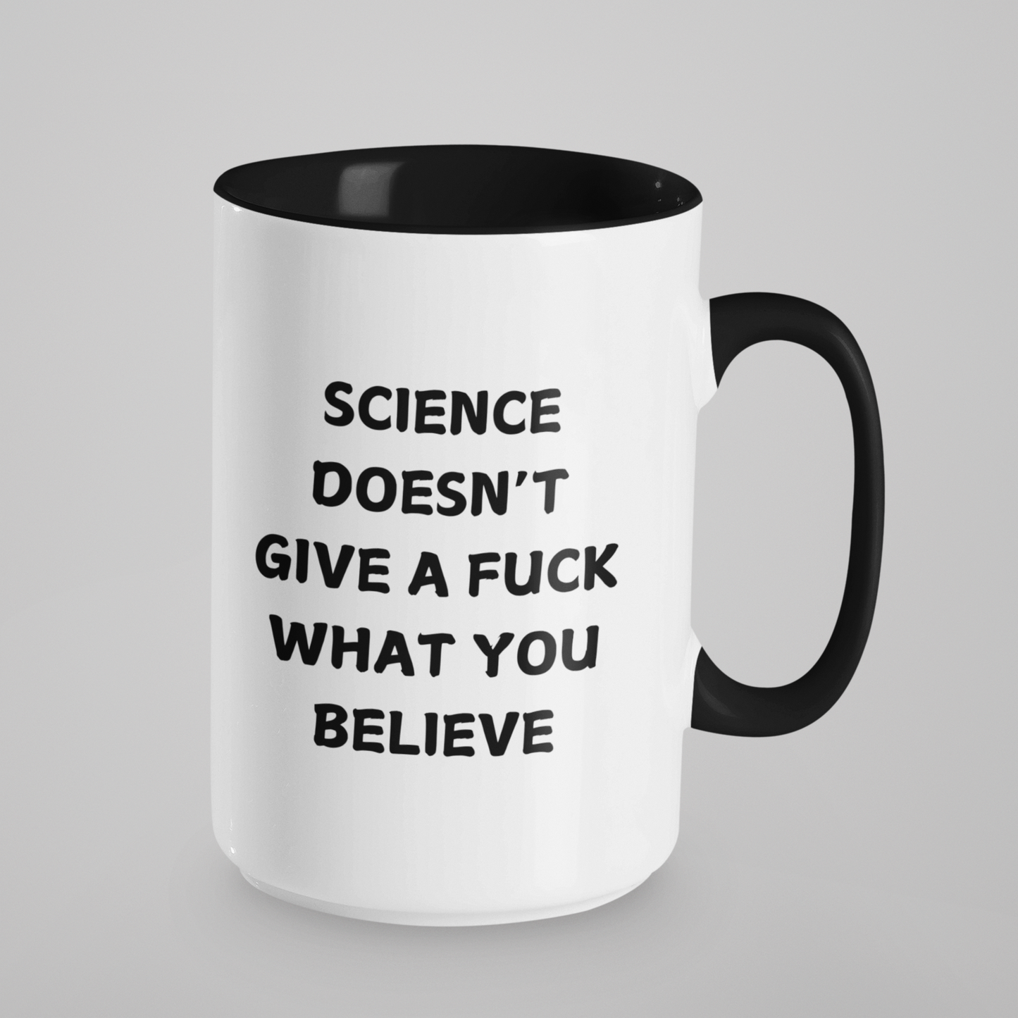 15 oz bold and edgy ceramic coffee mug designed for science enthusiasts and skeptics alike. The mug features a sleek black interior and handle, contrasting with its clean white exterior. Printed in bold, all-caps black lettering on one side is the unapologetic statement: "SCIENCE DOESN'T GIVE A F*** WHAT YOU BELIEVE."