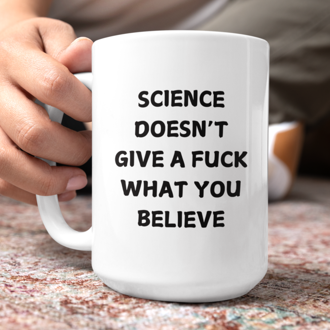 15 oz white ceramic coffee mug featuring bold black text that reads, "SCIENCE DOESN'T GIVE A F*CK WHAT YOU BELIEVE." The design uses an all-caps, sans-serif font with a slightly playful, bold look. Ideal for science enthusiasts, skeptics, and anyone who appreciates blunt humor with a dose of scientific truth.