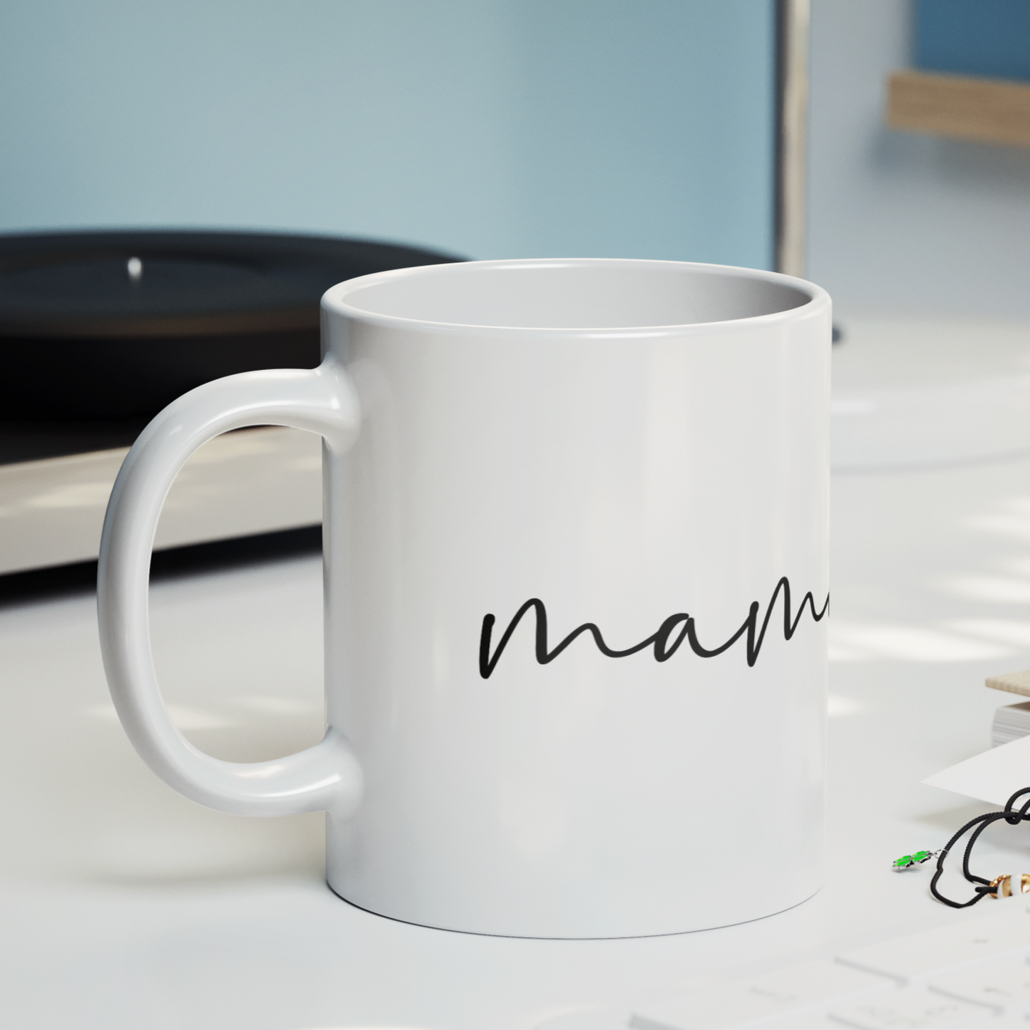Sleek 11 oz white ceramic coffee mug featuring a minimalist black handwritten-style script that reads “mama” with a small heart accent at the end. The mug has a smooth, glossy finish and a large, easy-grip handle. Perfect for gifting to moms who appreciate simple, modern design and a daily reminder of their cherished role. Ideal for Mother’s Day, birthdays, or everyday appreciation.