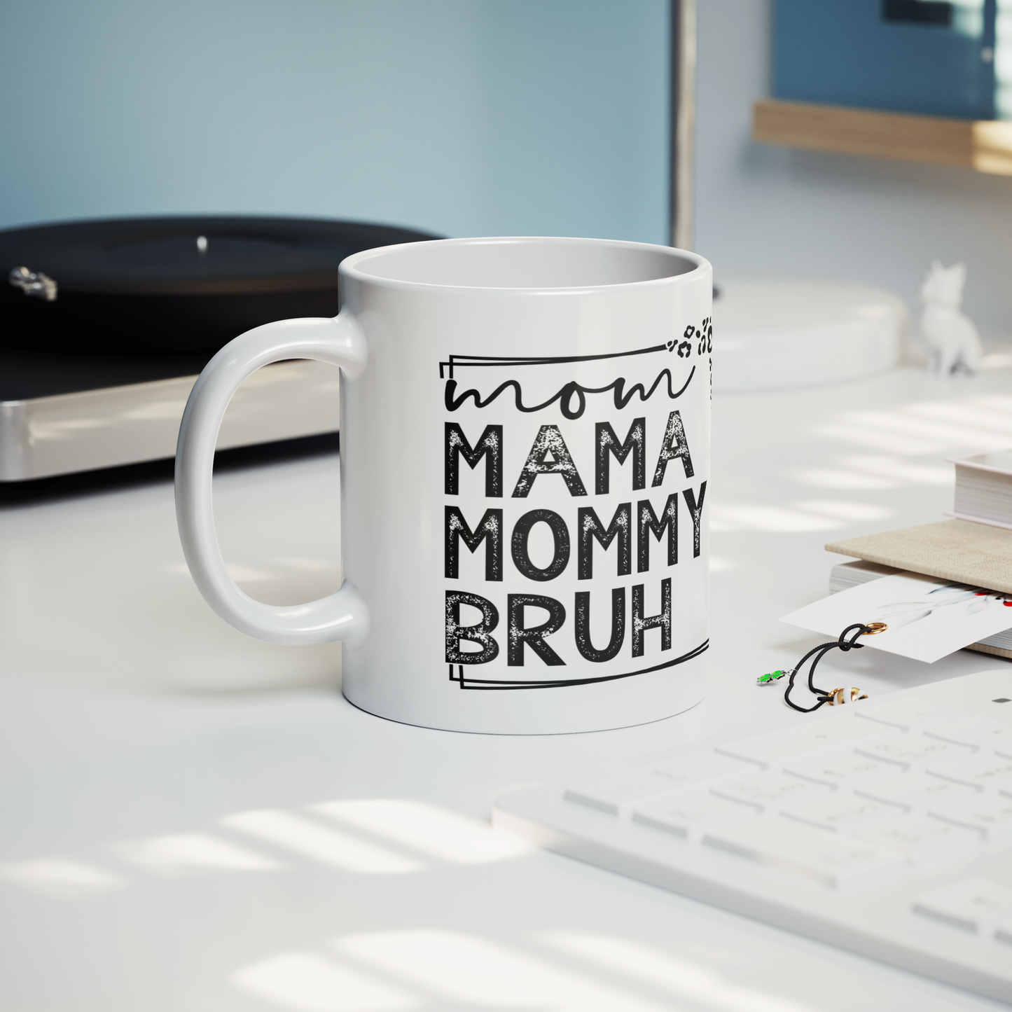11 oz white mug displaying a playful design that reads "mom MAMA MOMMY BRUH" in black, framed with leopard print details. A funny gift for moms with a sense of humor.