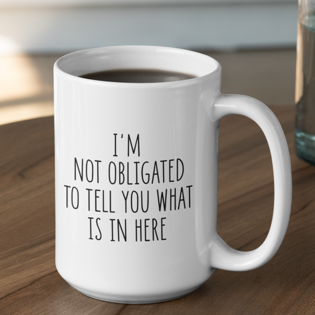 Simple yet impactful 15 oz white mug featuring the witty statement "I'M NOT OBLIGATED TO TELL YOU WHAT IS IN HERE" in a clear black font. Perfect for those with a dry wit and a desire for a bit of beverage privacy.