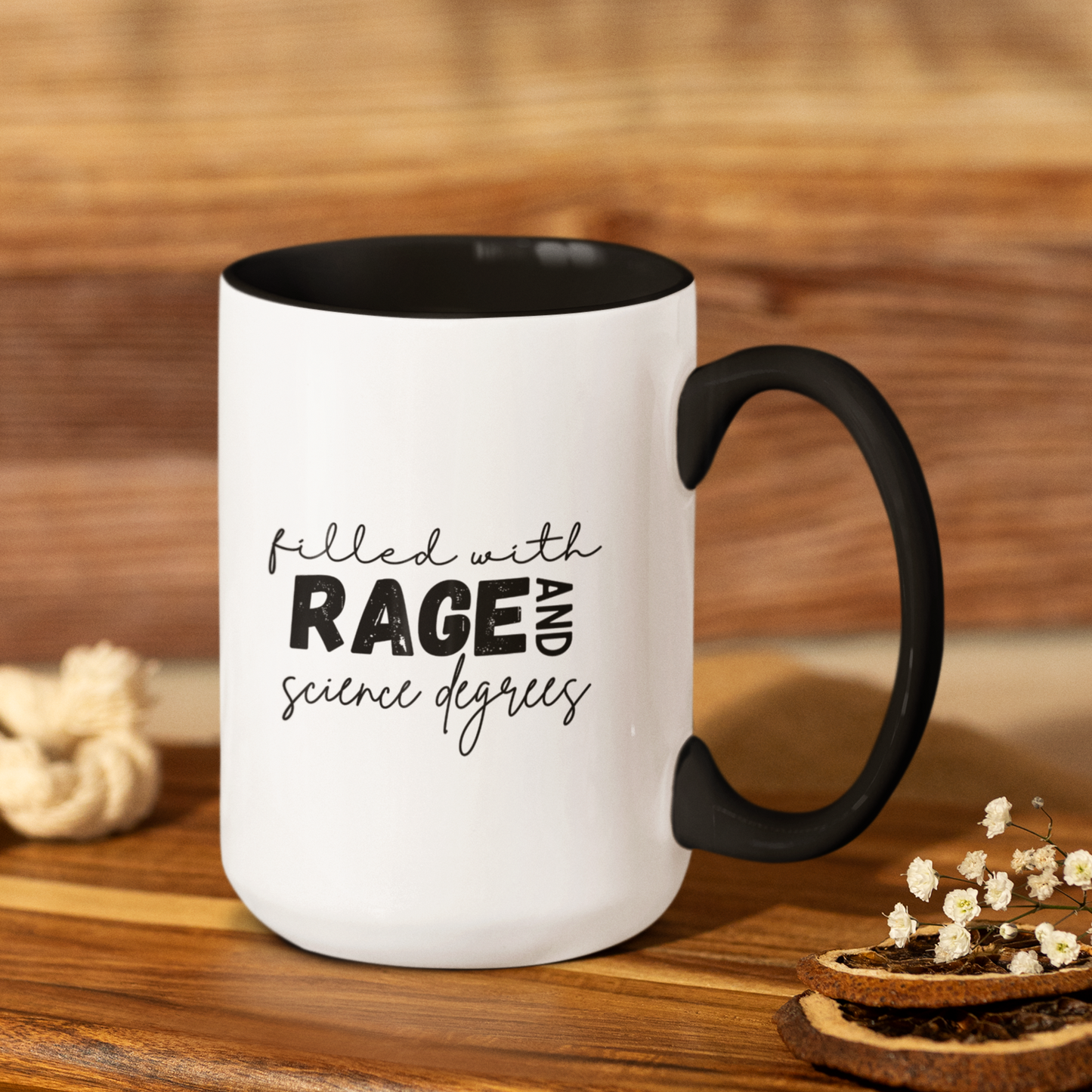 15 oz Stylish ceramic coffee mug with a matte black handle and interior, contrasted by a crisp white exterior. The front features a bold, playful design with the text: "filled with RAGE AND science degrees" in a mix of handwritten and bold block fonts. Perfect for scientists, researchers, and academics who appreciate humor and a little edge with their morning coffee.