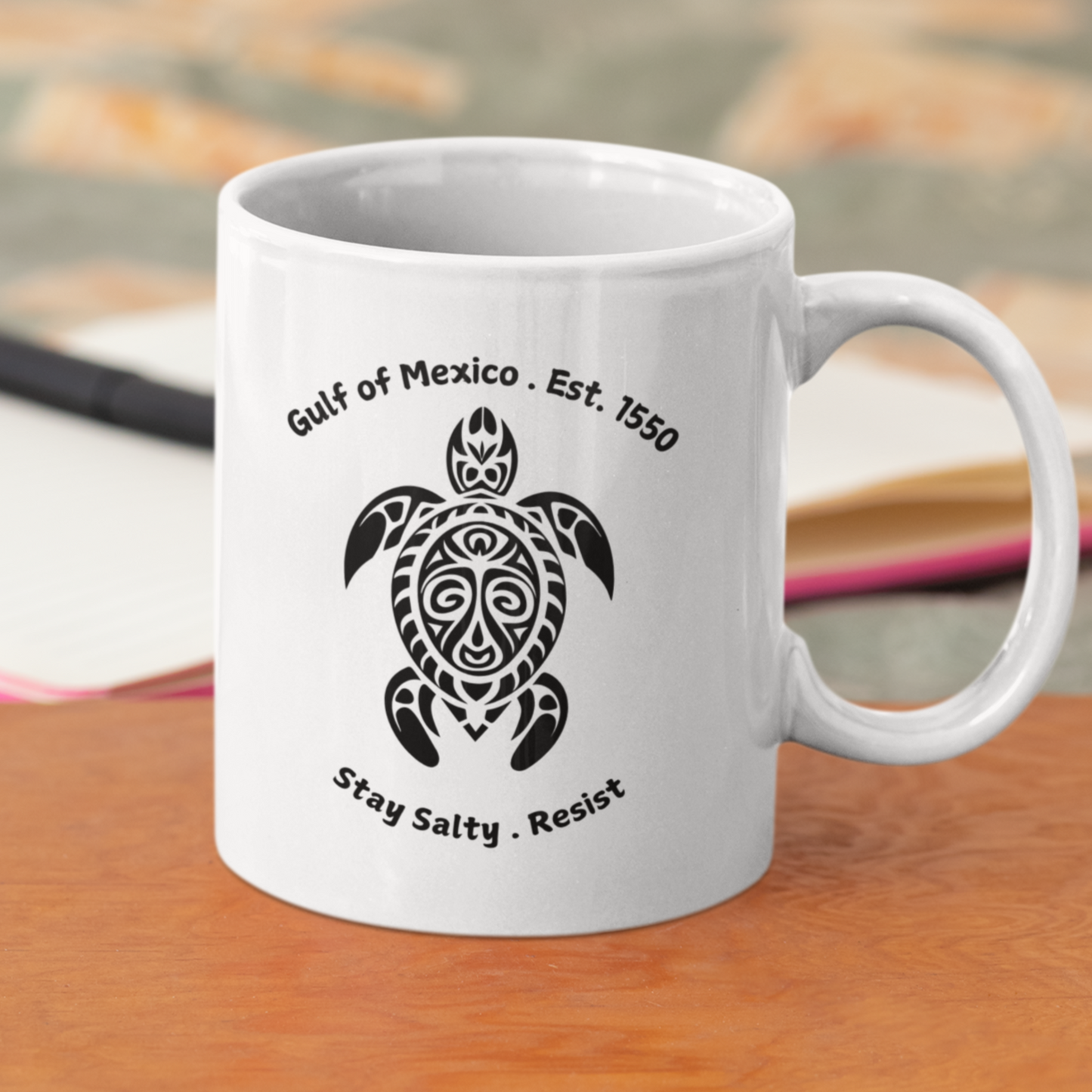 11 oz High-quality ceramic coffee mug featuring a bold, tribal-style sea turtle graphic in black. The design showcases the text “Gulf of Mexico • Est. 1550” above the turtle and “Stay Salty • Resist” below, giving it a coastal, eco-conscious vibe. The mug is finished in a glossy white glaze with a comfortable, large curved handle for easy grip. Ideal for ocean lovers, environmental advocates, or anyone who appreciates unique, artistic drinkware with a message of resilience and coastal pride.