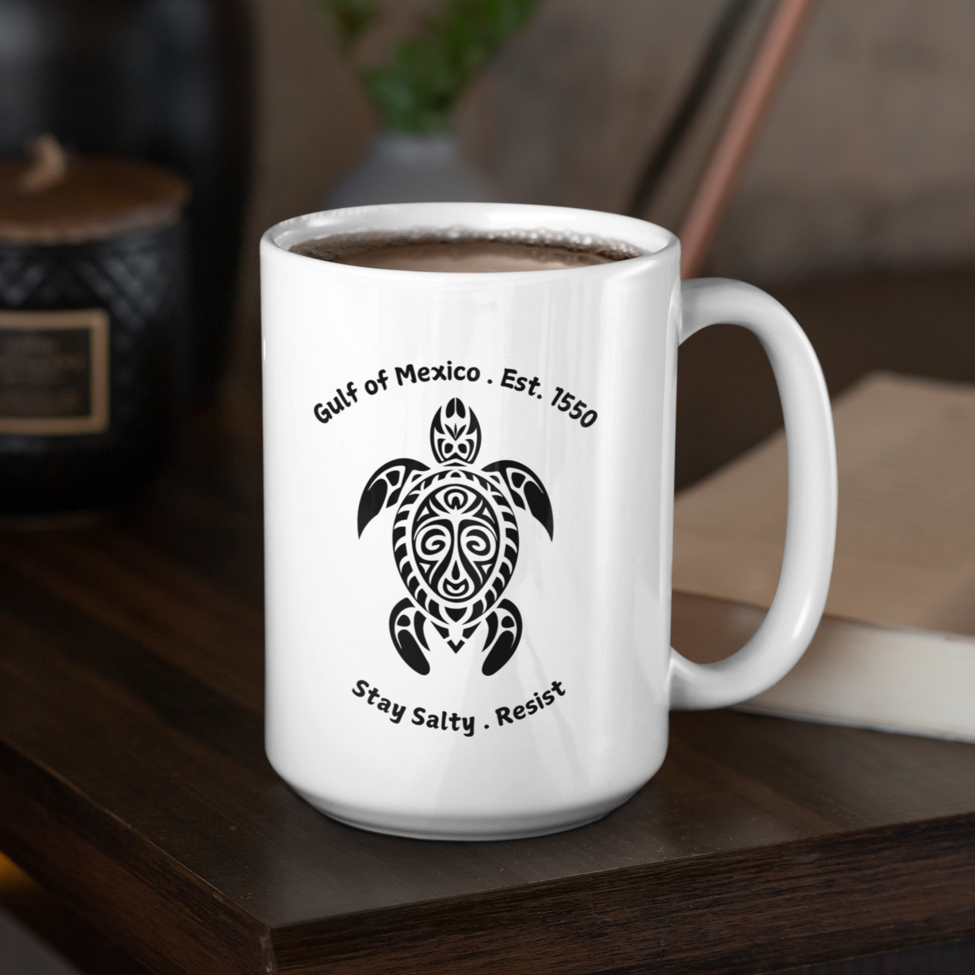 15 oz High-quality ceramic coffee mug featuring a bold, tribal-style sea turtle graphic in black. The design showcases the text “Gulf of Mexico • Est. 1550” above the turtle and “Stay Salty • Resist” below, giving it a coastal, eco-conscious vibe. The mug is finished in a glossy white glaze with a comfortable, large curved handle for easy grip. Ideal for ocean lovers, environmental advocates, or anyone who appreciates unique, artistic drinkware with a message of resilience and coastal pride.