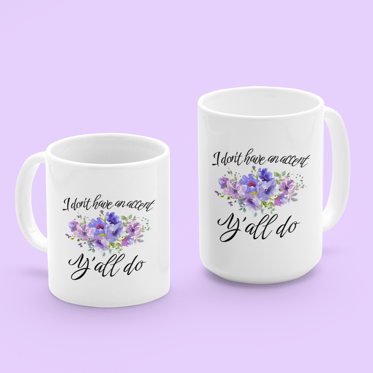 11 & 15 oz White ceramic coffee mug featuring a charming, southern-inspired design. The front showcases a whimsical quote in elegant, black cursive font that reads, “I don’t have an accent, Y’all do.” Between the two lines of text, there’s a delicate watercolor illustration of purple and lavender flowers with green foliage, adding a soft, feminine touch.