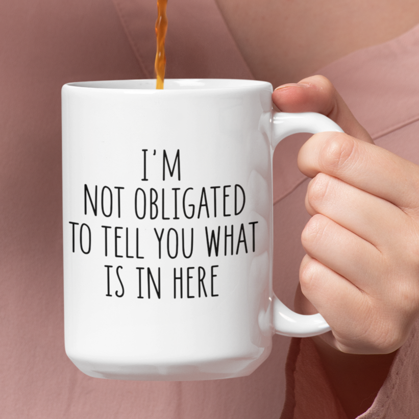 Simple yet impactful 15 oz white mug featuring the witty statement "I'M NOT OBLIGATED TO TELL YOU WHAT IS IN HERE" in a clear black font. Perfect for those with a dry wit and a desire for a bit of beverage privacy.