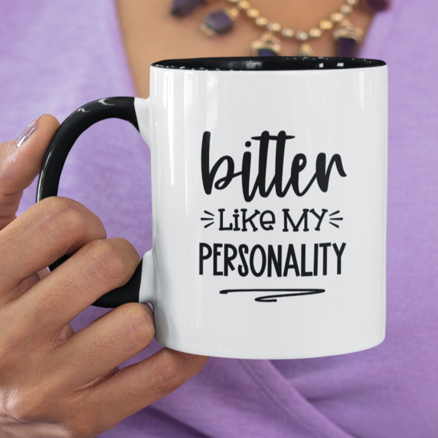 White ceramic mug with a sleek black handle and rim, featuring the bold, sarcastic quote “bitter like my personality” in a stylish black font. Perfect for lovers of dry humor and coffee with a bite, this mug adds a fun edge to your morning routine.