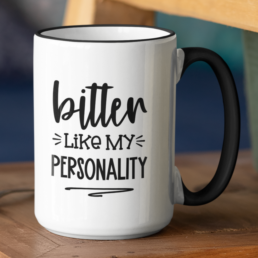 White ceramic mug with a sleek black handle and rim, featuring the bold, sarcastic quote “bitter like my personality” in a stylish black font. Perfect for lovers of dry humor and coffee with a bite, this mug adds a fun edge to your morning routine.