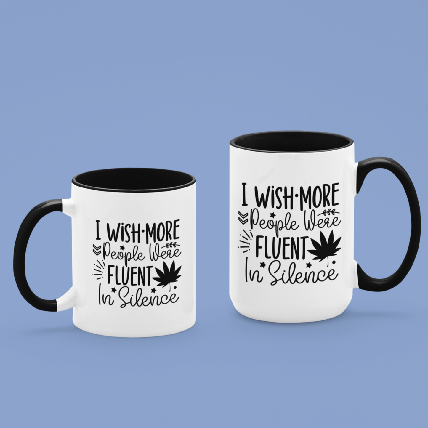 Charming white ceramic mug with a black interior and matching handle, featuring a witty black typography design that says, “I wish more people were fluent in silence,” alongside playful icons like stars, leaves, and a bold maple leaf silhouette. A perfect gift for introverts, tea lovers, or anyone who appreciates peace and clever design.
