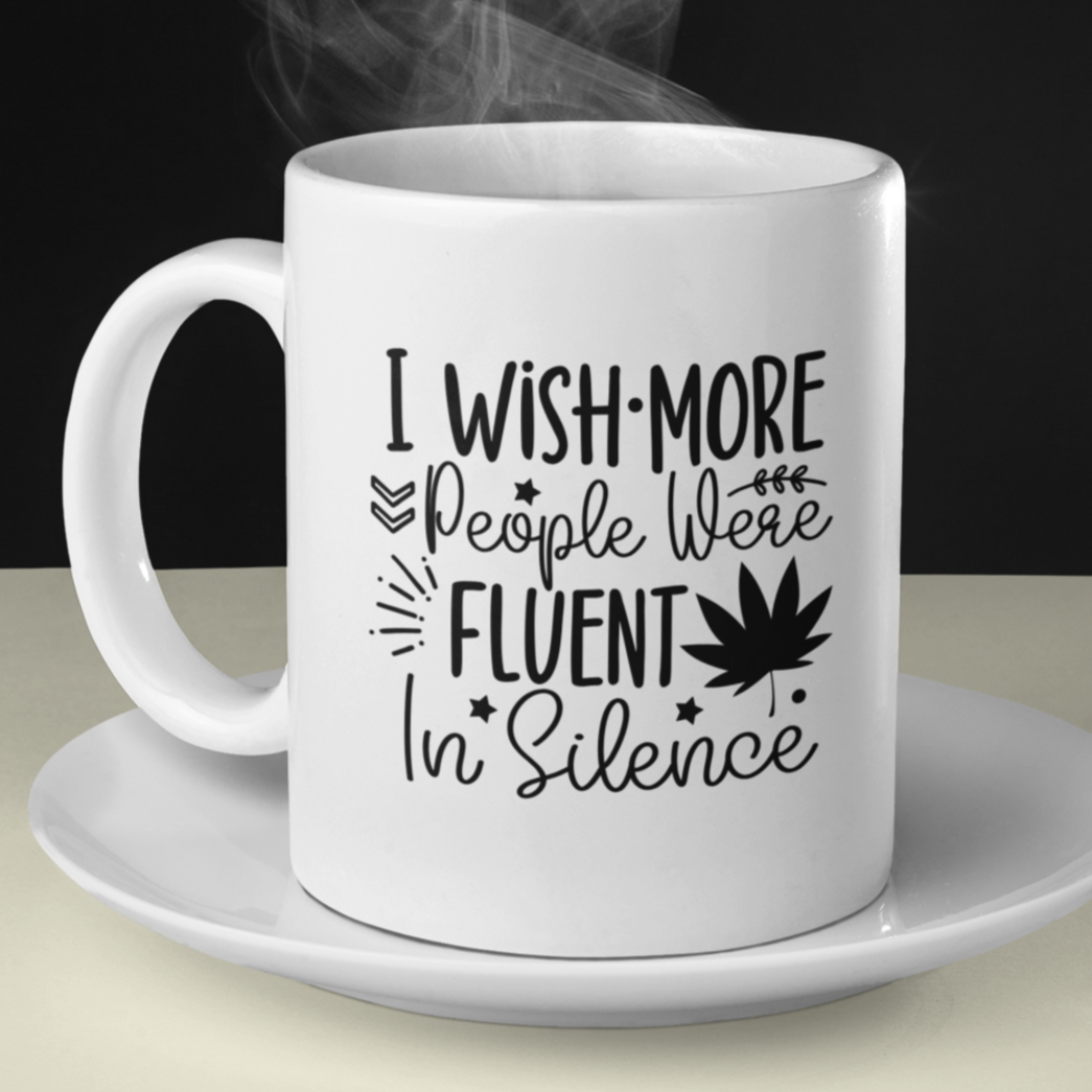 Stylish white ceramic mug with a sassy black text design that reads, “I wish more people were fluent in silence,” accented with playful stars, leaves, and a bold graphic of a maple leaf. Minimalist aesthetic—perfect for introverts, deep thinkers, or anyone who values peace and quiet. Durable, dishwasher-safe, and great for gifting or personal use with hot beverages like coffee or tea.