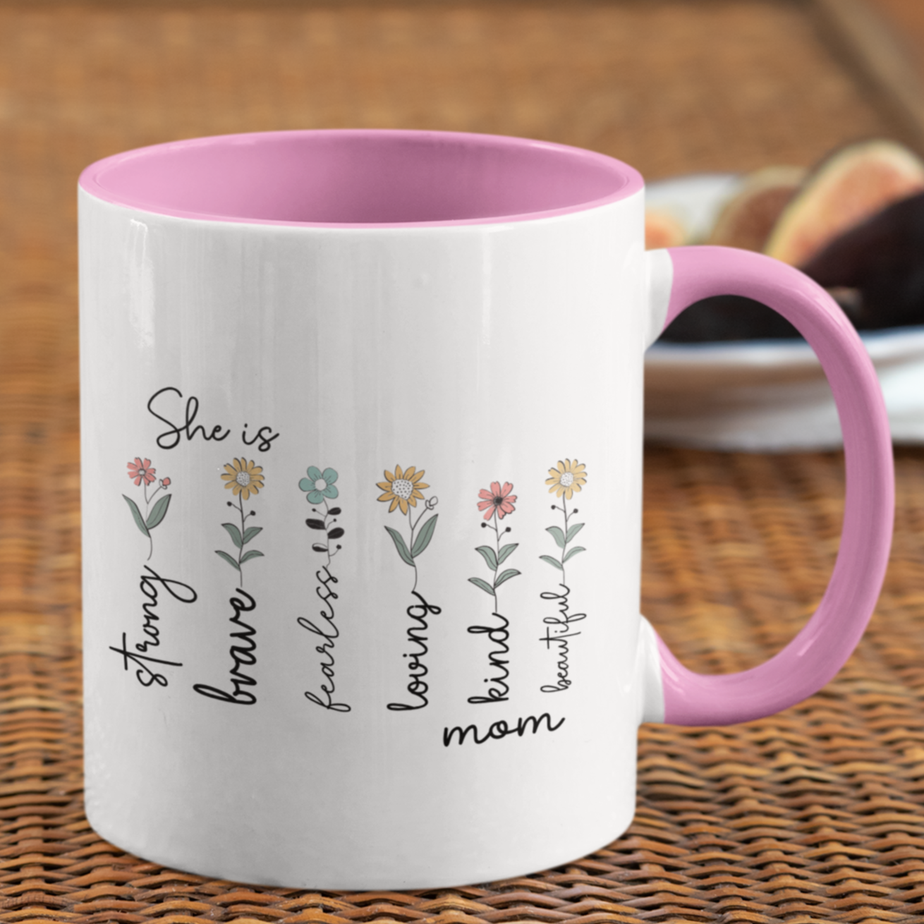 Charming 15 oz ceramic coffee mug with a glossy white exterior, soft pink interior, and matching pink handle. The design features delicate hand-drawn flowers paired with uplifting words that read: “She is strong, brave, fearless, loving, kind, mom, beautiful.” The heartfelt text and pastel floral accents create a warm, inspirational gift perfect for Mother's Day, birthdays, or everyday appreciation.