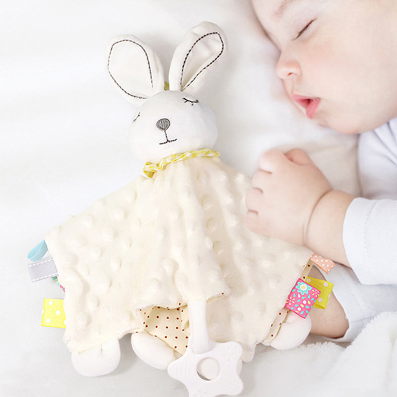 baby sleeping and holding a cream colored bunny chenille toy