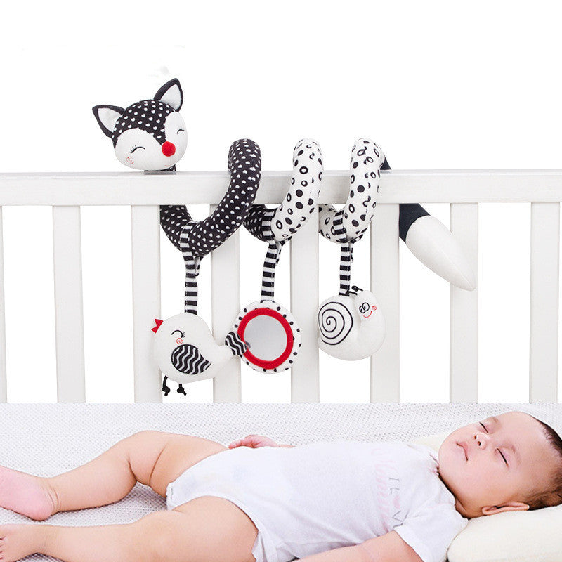 black and white spiral toy on crib rail showing sleeping infant in crib