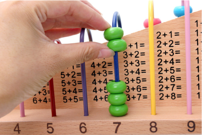 fingers moving green beads over the top of abacus
