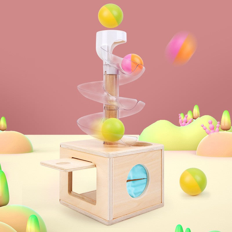 this image shows the colorful wooden balls in action rolling down the clear plastic track into the wooden box below. There is a door shown open on the side of the box
