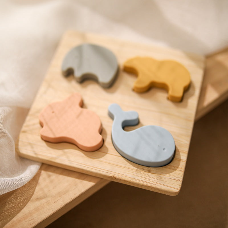 wooden base with cutouts in shapes with matching silicone shapes of whale, bunny, bear and elephant. soft pastel colors