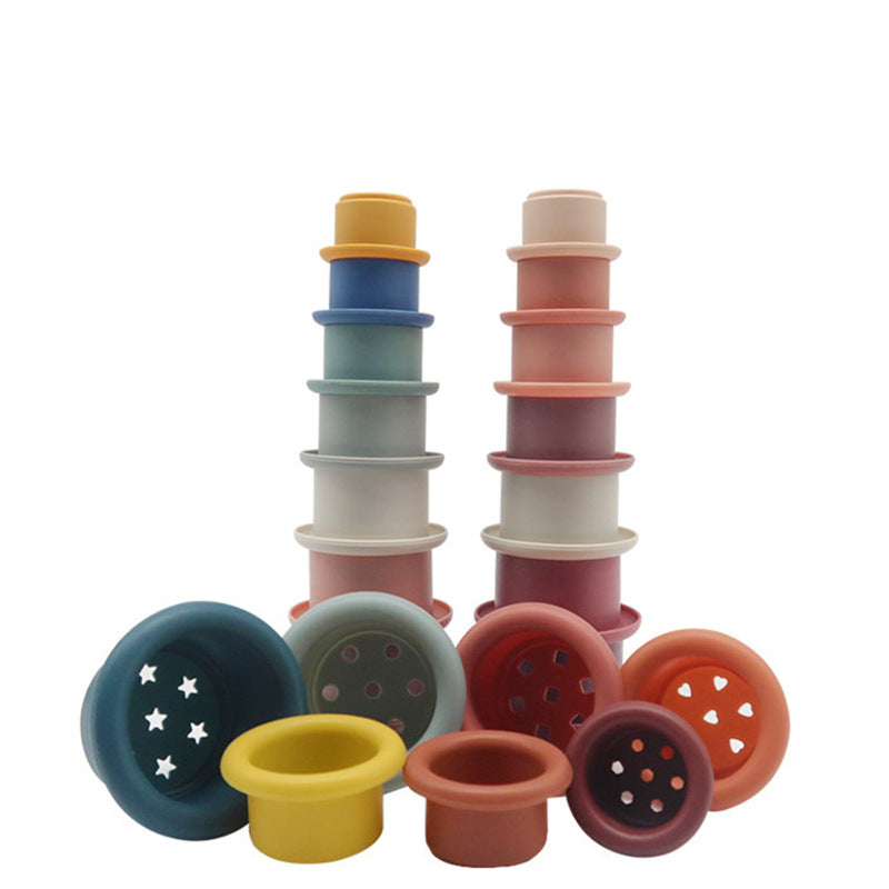 stacked silicone cups with multiple colors and holes of different shapes in the bottom of the cups on a white background