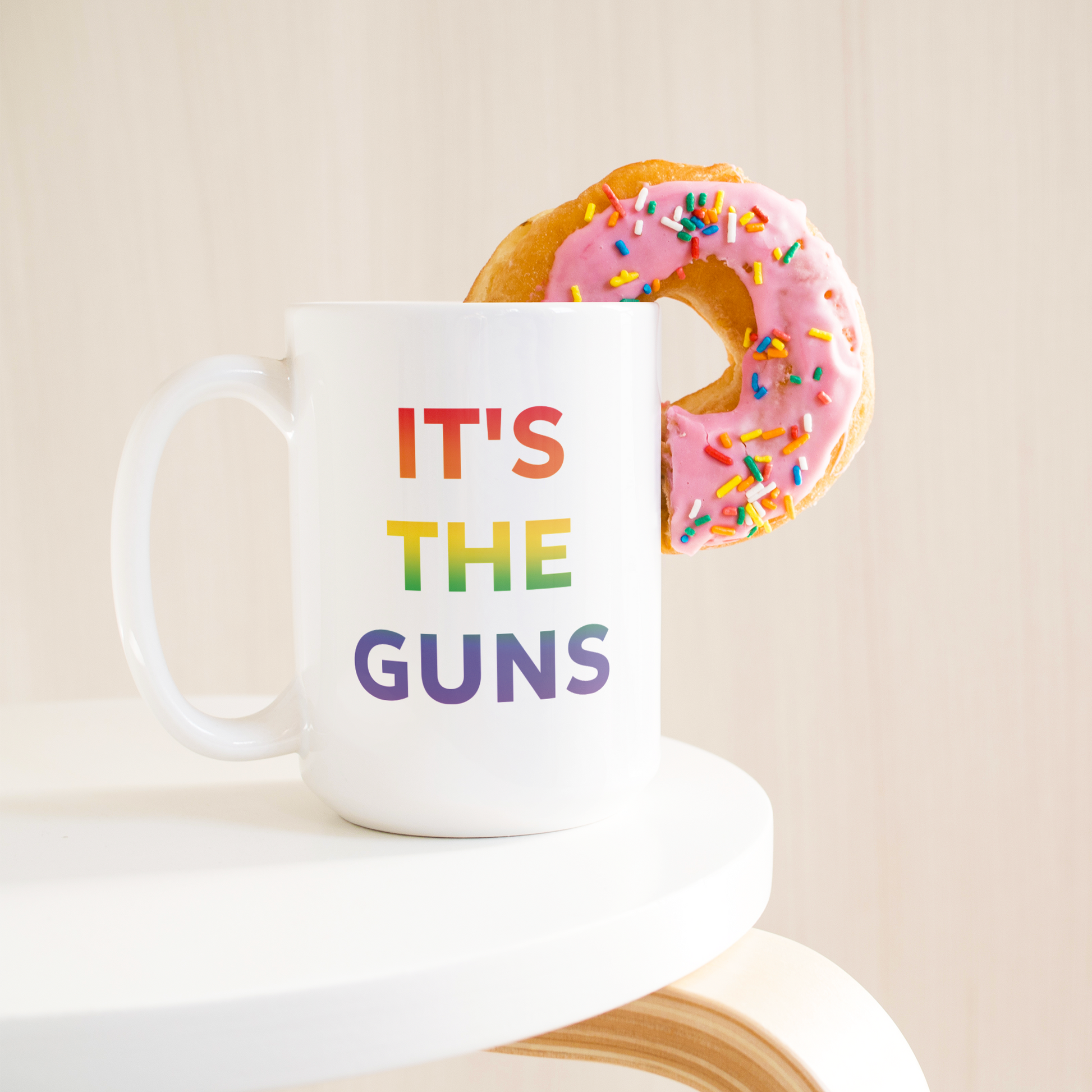 Its_The_Guns_Coffee_Mug_Supporting_Gun__15ozWhiteMugLifetsyleDonutLH_Mockup.png
