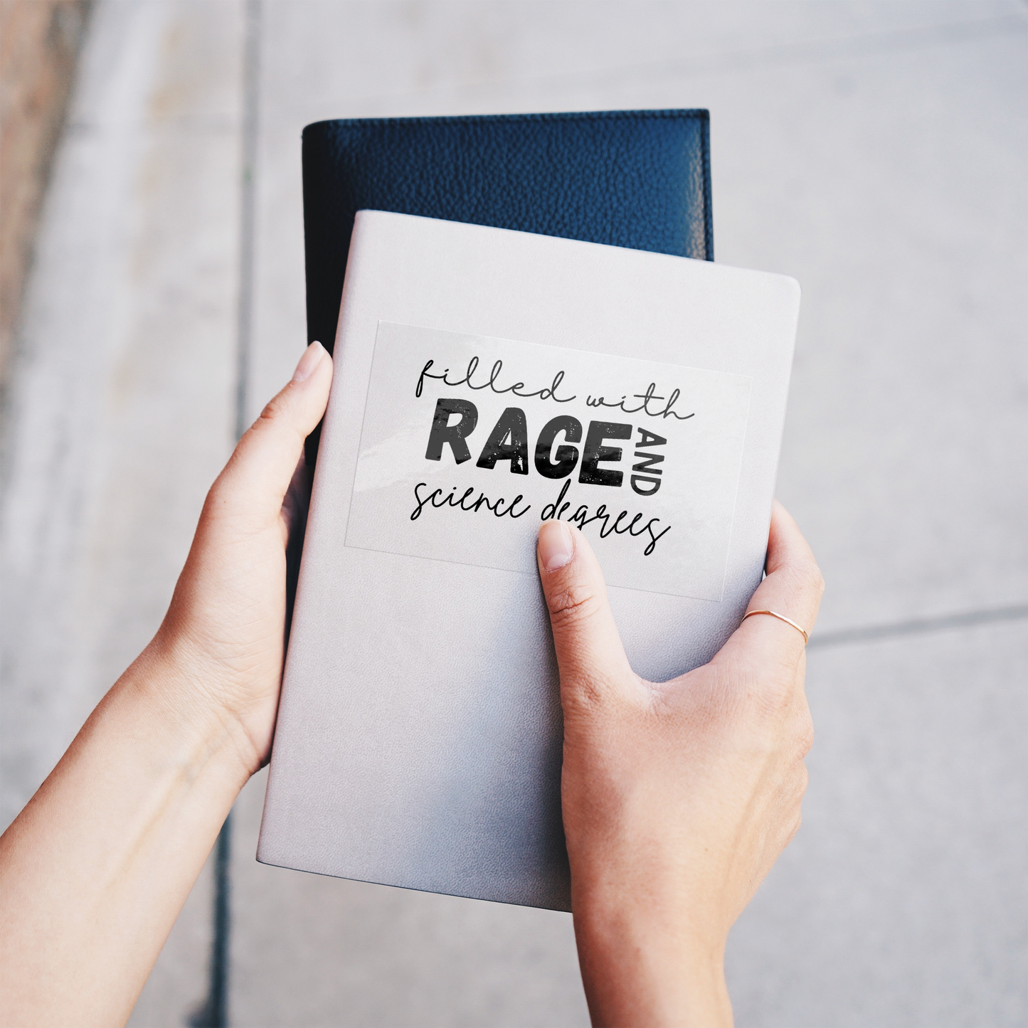 Sticker design featuring a bold, empowering quote: “Filled with RAGE and science degrees.” The word “RAGE” is in all caps, distressed block letters for a dramatic, rebellious feel, while the rest of the phrase is in an elegant, handwritten script that contrasts with the boldness. Perfect for laptops, water bottles, or notebooks—ideal for scientists, students, feminists, and activists who embrace both intellect and passion. Matte finish, durable vinyl.