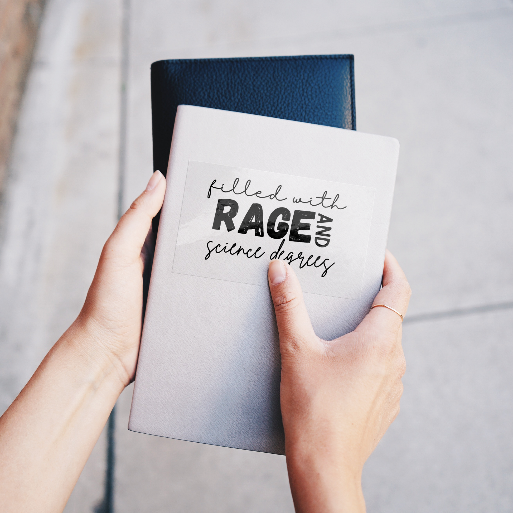 Sticker design featuring a bold, empowering quote: “Filled with RAGE and science degrees.” The word “RAGE” is in all caps, distressed block letters for a dramatic, rebellious feel, while the rest of the phrase is in an elegant, handwritten script that contrasts with the boldness. Perfect for laptops, water bottles, or notebooks—ideal for scientists, students, feminists, and activists who embrace both intellect and passion. Matte finish, durable vinyl.