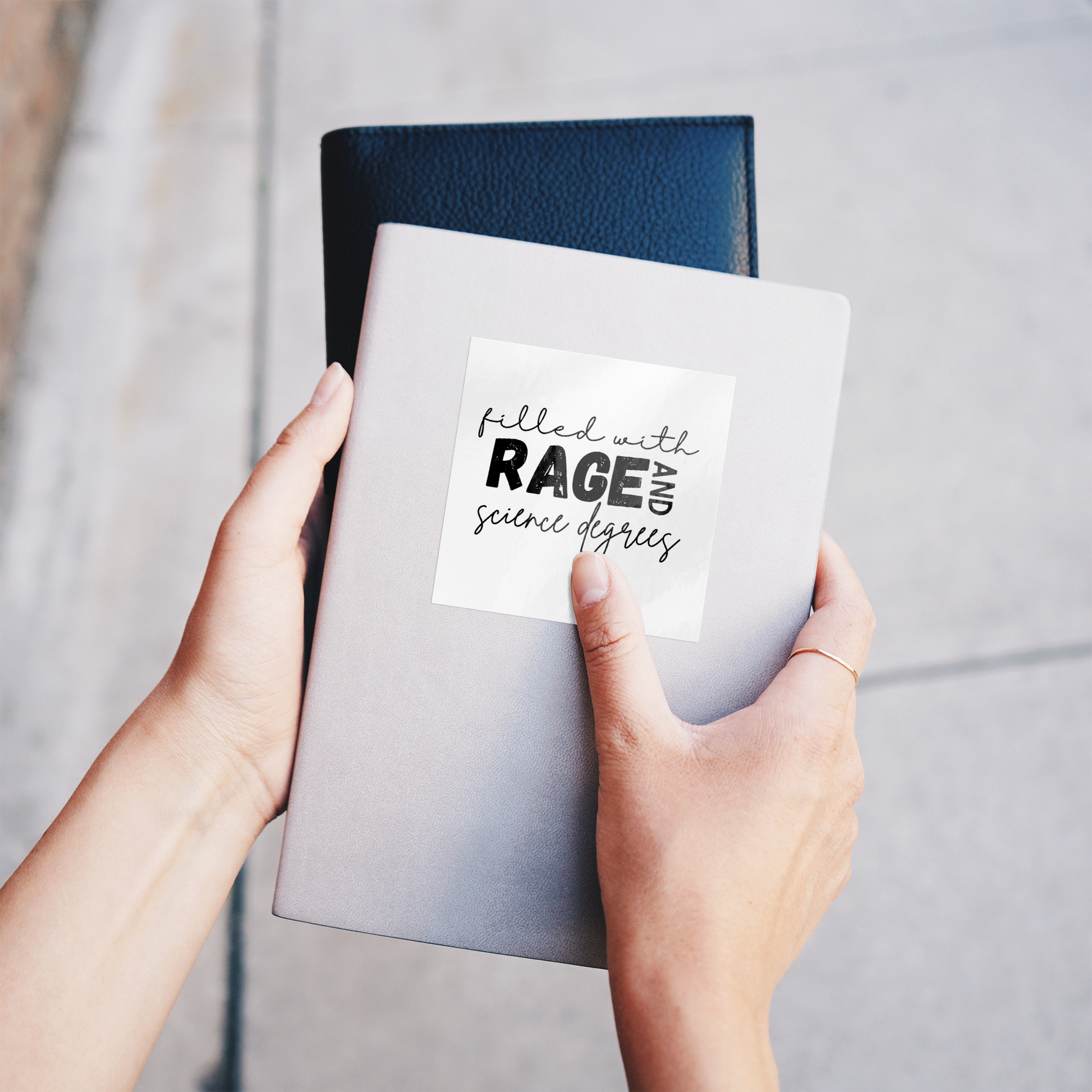 Sticker design featuring a bold, empowering quote: “Filled with RAGE and science degrees.” The word “RAGE” is in all caps, distressed block letters for a dramatic, rebellious feel, while the rest of the phrase is in an elegant, handwritten script that contrasts with the boldness. Perfect for laptops, water bottles, or notebooks—ideal for scientists, students, feminists, and activists who embrace both intellect and passion. Matte finish, durable vinyl.