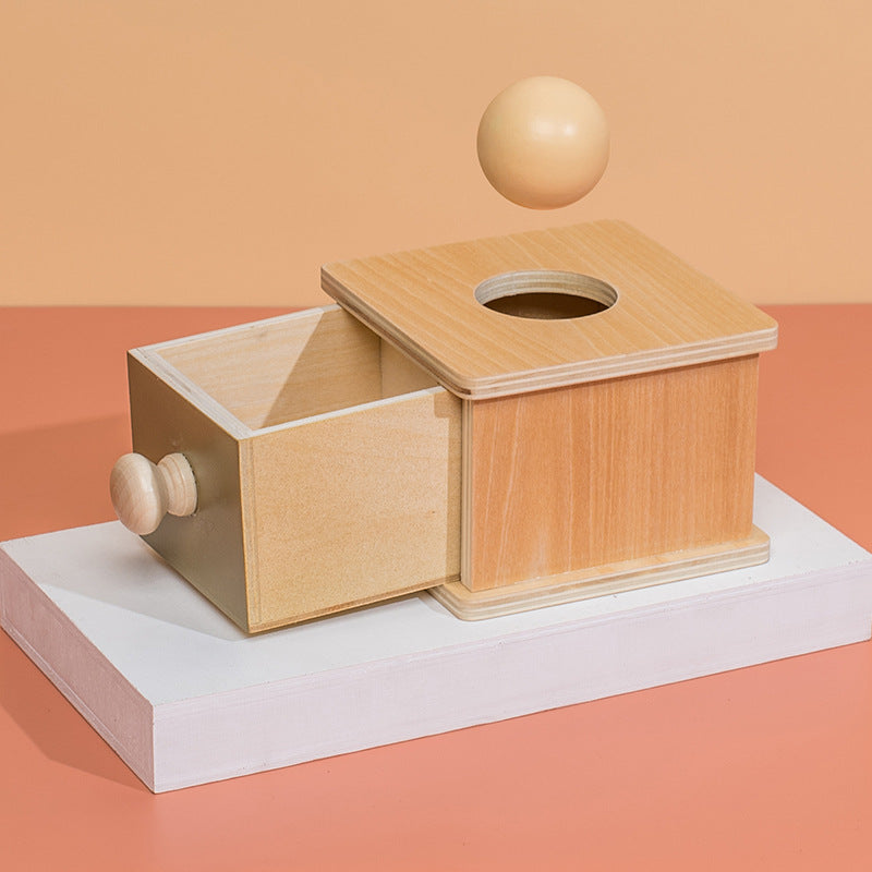 wooden object permanence box with balls that drop into the hole on top and fall into a drawer