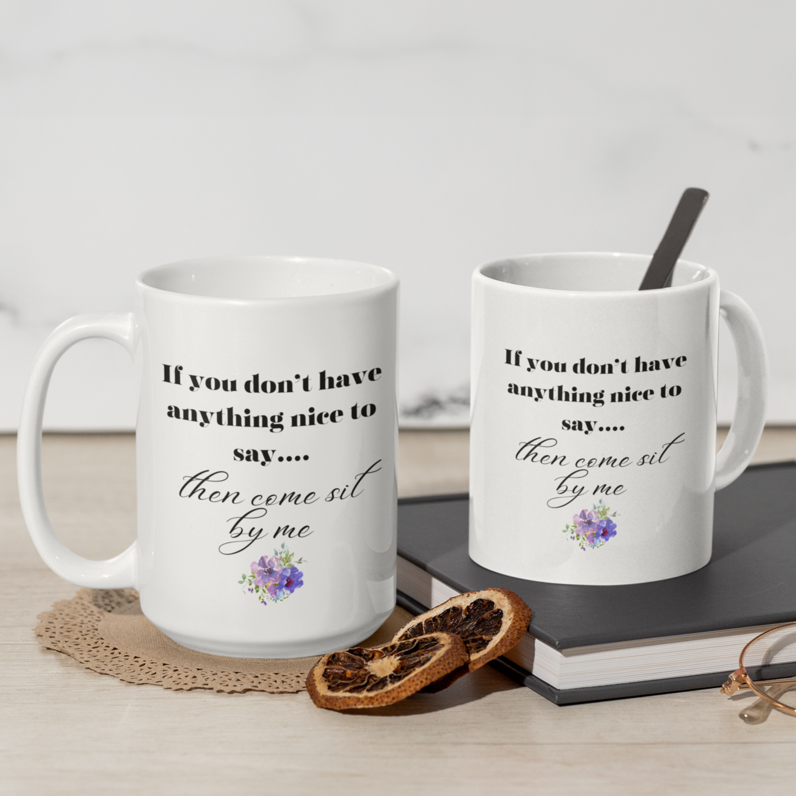 11 & 15 oz White ceramic coffee mug featuring a humorous and sassy quote in elegant black script: "If you don't have anything nice to say... then come sit by me." Below the text is a delicate floral graphic with purple and pink flowers and soft green leaves, adding a charming touch. Perfect for tea or coffee lovers with a sense of humor! Ideal gift for friends, coworkers, or anyone who loves witty, playful mugs.