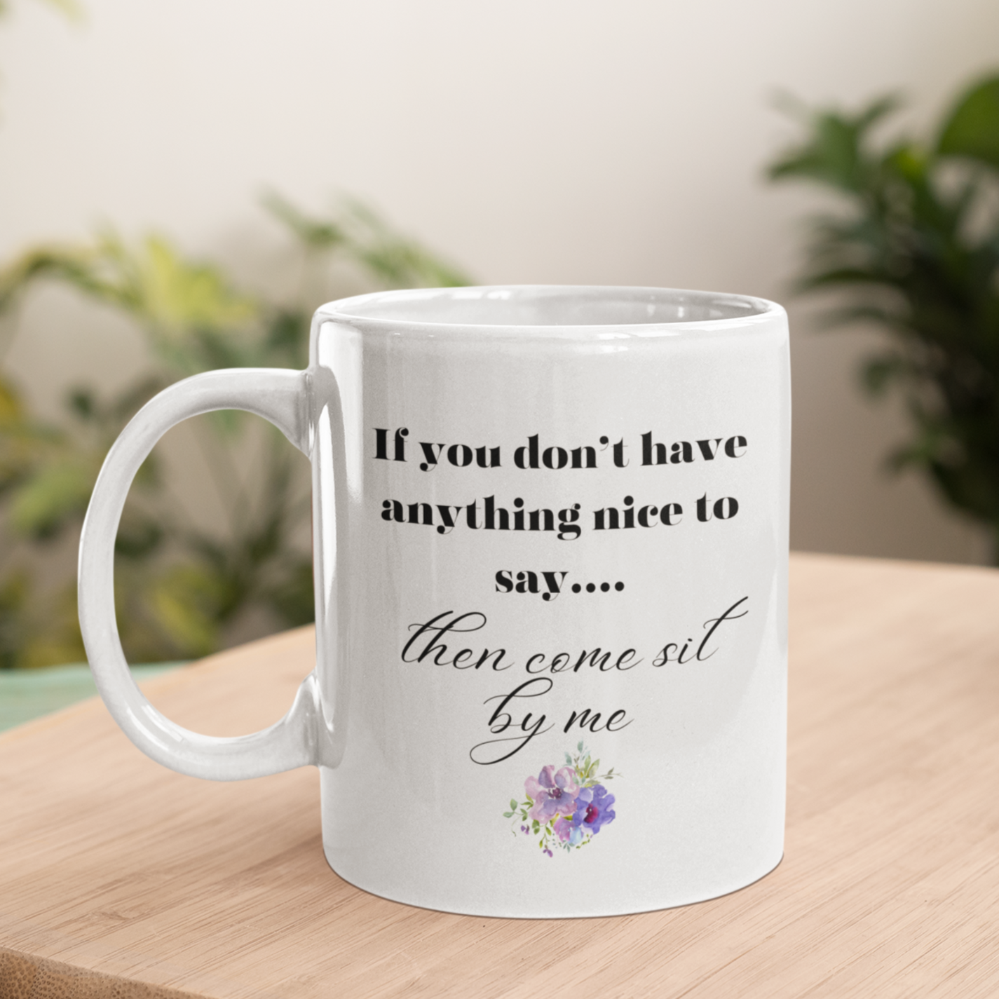 11 oz White ceramic coffee mug featuring a humorous and sassy quote in elegant black script: "If you don't have anything nice to say... then come sit by me." Below the text is a delicate floral graphic with purple and pink flowers and soft green leaves, adding a charming touch. Perfect for tea or coffee lovers with a sense of humor! Ideal gift for friends, coworkers, or anyone who loves witty, playful mugs.