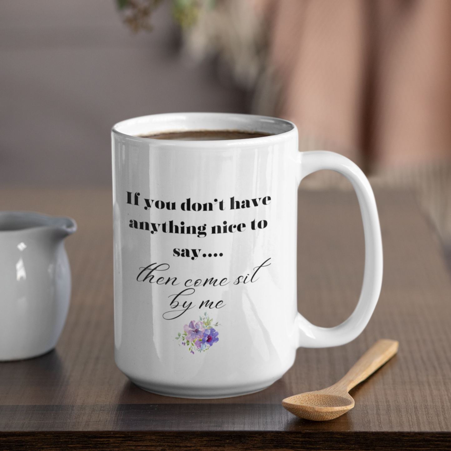 15 oz White ceramic coffee mug featuring a humorous and sassy quote in elegant black script: "If you don't have anything nice to say... then come sit by me." Below the text is a delicate floral graphic with purple and pink flowers and soft green leaves, adding a charming touch. Perfect for tea or coffee lovers with a sense of humor! Ideal gift for friends, coworkers, or anyone who loves witty, playful mugs.