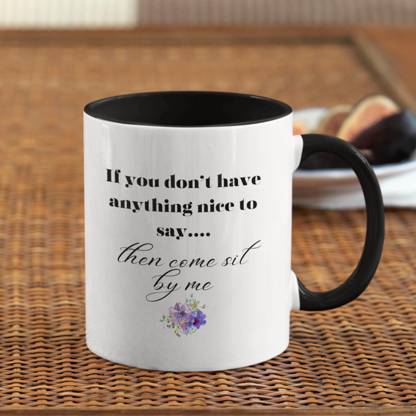 11 oz White ceramic coffee mug with a black handle and interior, featuring a playful and humorous quote printed in elegant black fonts. The text reads: "If you don’t have anything nice to say... then come sit by me." The phrase is styled with a combination of bold serif and flowing script fonts for emphasis. Below the quote, there’s a charming floral graphic with soft purple and pink flowers accented by green leaves.