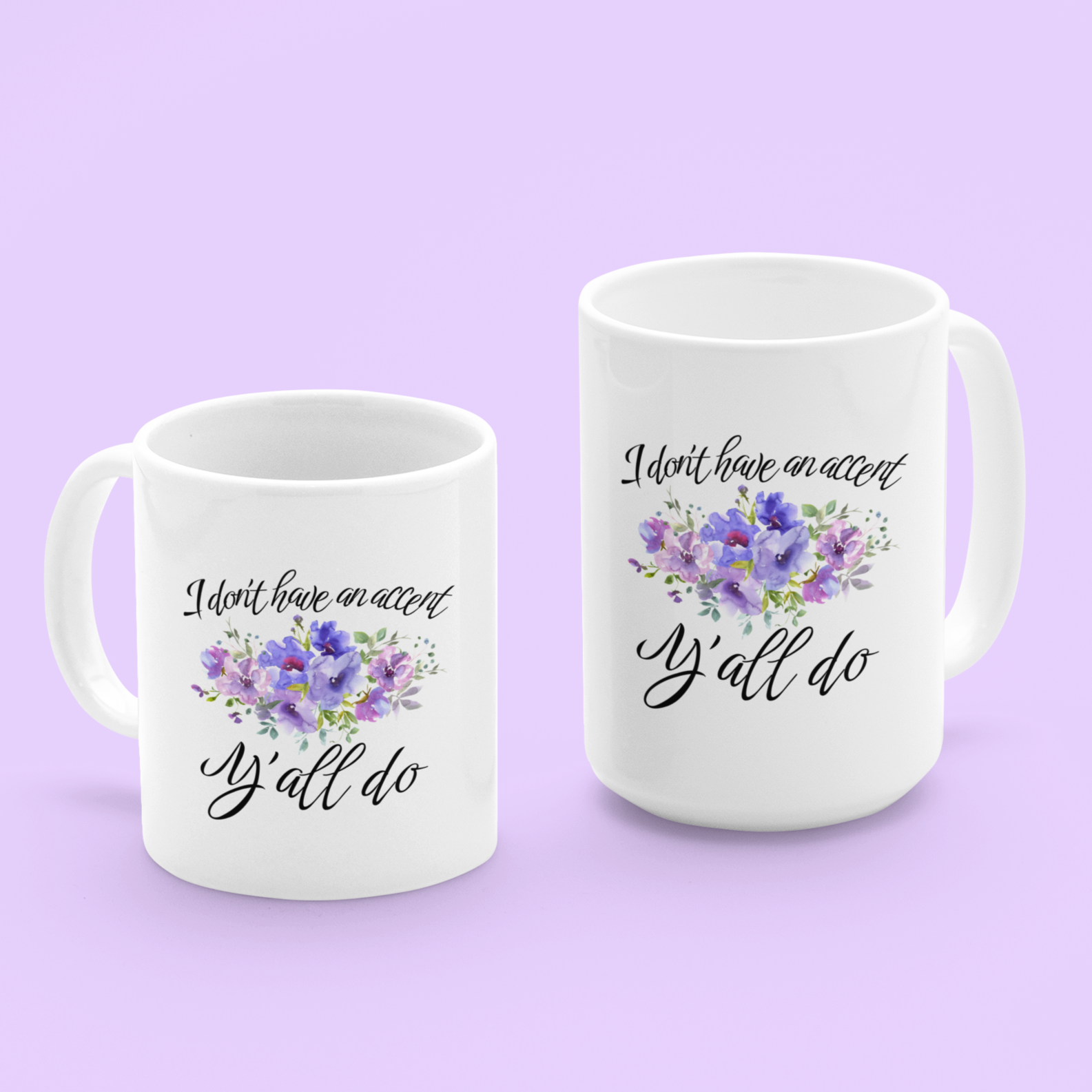 11 & 15 oz White ceramic coffee mug featuring a charming, southern-inspired design. The front showcases a whimsical quote in elegant, black cursive font that reads, “I don’t have an accent, Y’all do.” Between the two lines of text, there’s a delicate watercolor illustration of purple and lavender flowers with green foliage, adding a soft, feminine touch.