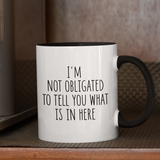 Simple yet impactful 11 oz white mug with black accents, featuring the witty statement "I'M NOT OBLIGATED TO TELL YOU WHAT IS IN HERE" in a clear black font. Perfect for those with a dry wit and a desire for a little beverage privacy.
