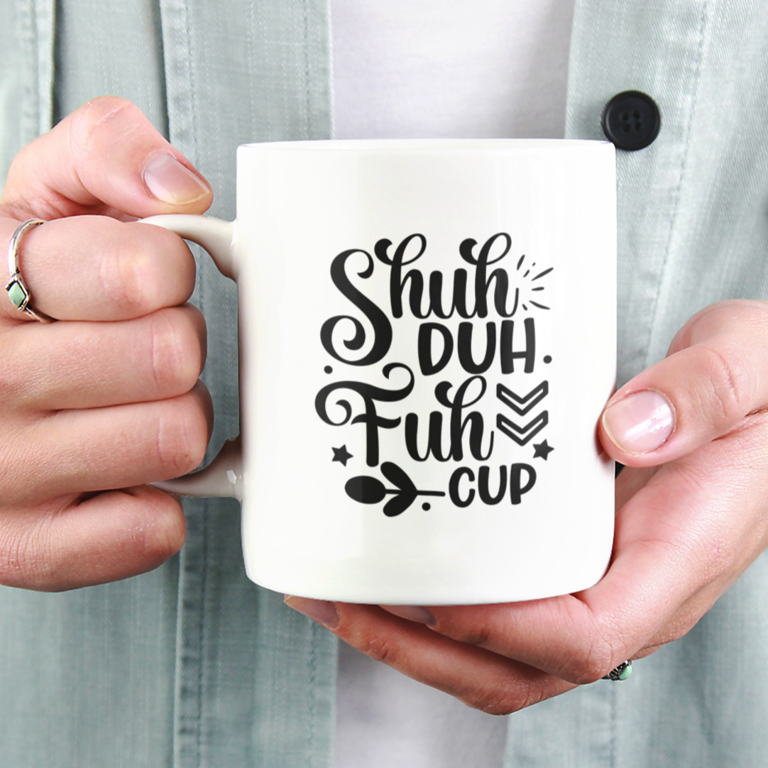 White ceramic coffee mug featuring a bold and cheeky black design that reads, “Shuh Duh Fuh Cup” in a playful script and block font mix, with whimsical accents like arrows, stars, and leaves. Perfect for anyone with a sarcastic sense of humor, this mug makes a great gift or daily dose of sass for coffee lovers. Durable, microwave and dishwasher safe.