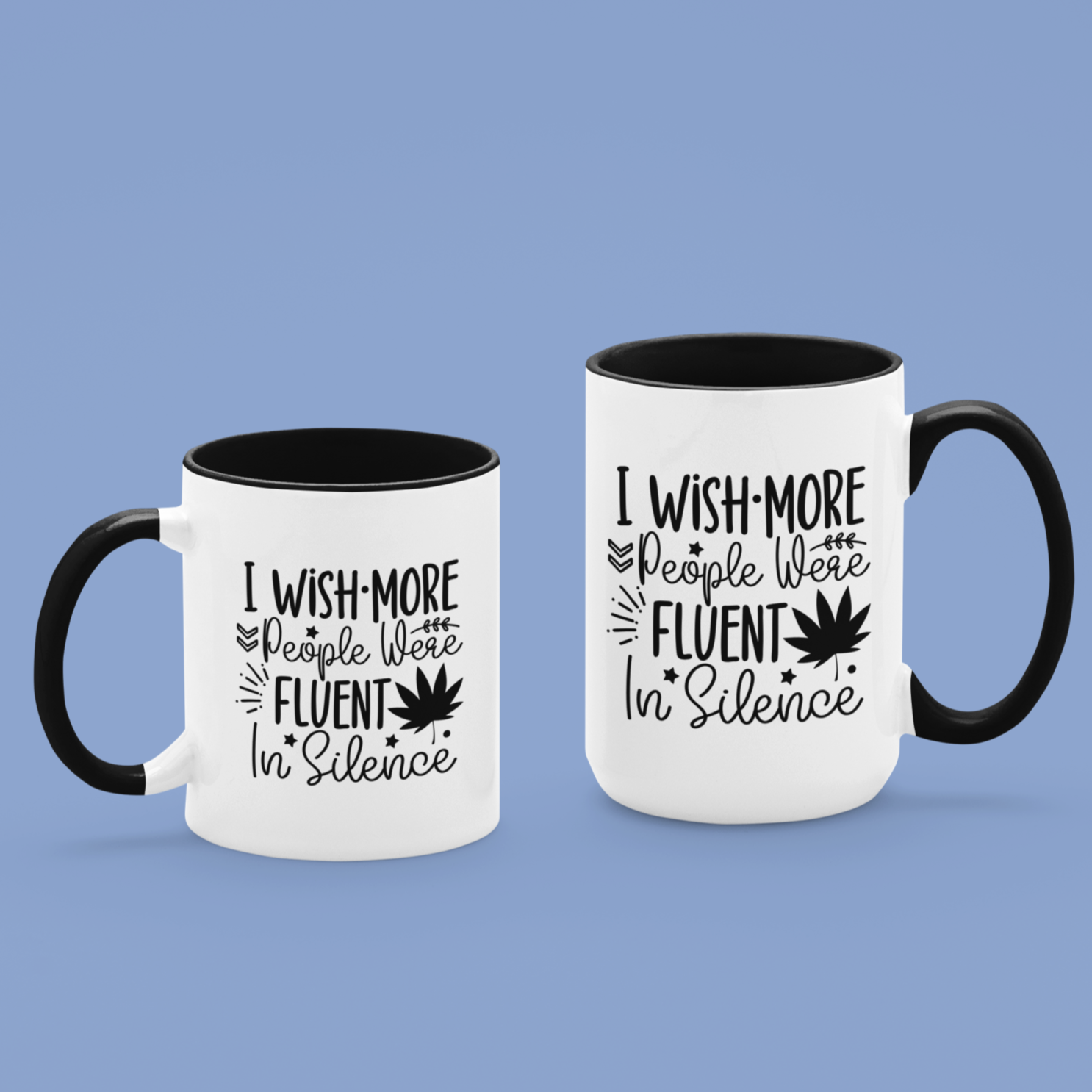 Charming white ceramic mug with a black interior and matching handle, featuring a witty black typography design that says, “I wish more people were fluent in silence,” alongside playful icons like stars, leaves, and a bold maple leaf silhouette.  A perfect gift for introverts, tea lovers, or anyone who appreciates peace and clever design.
